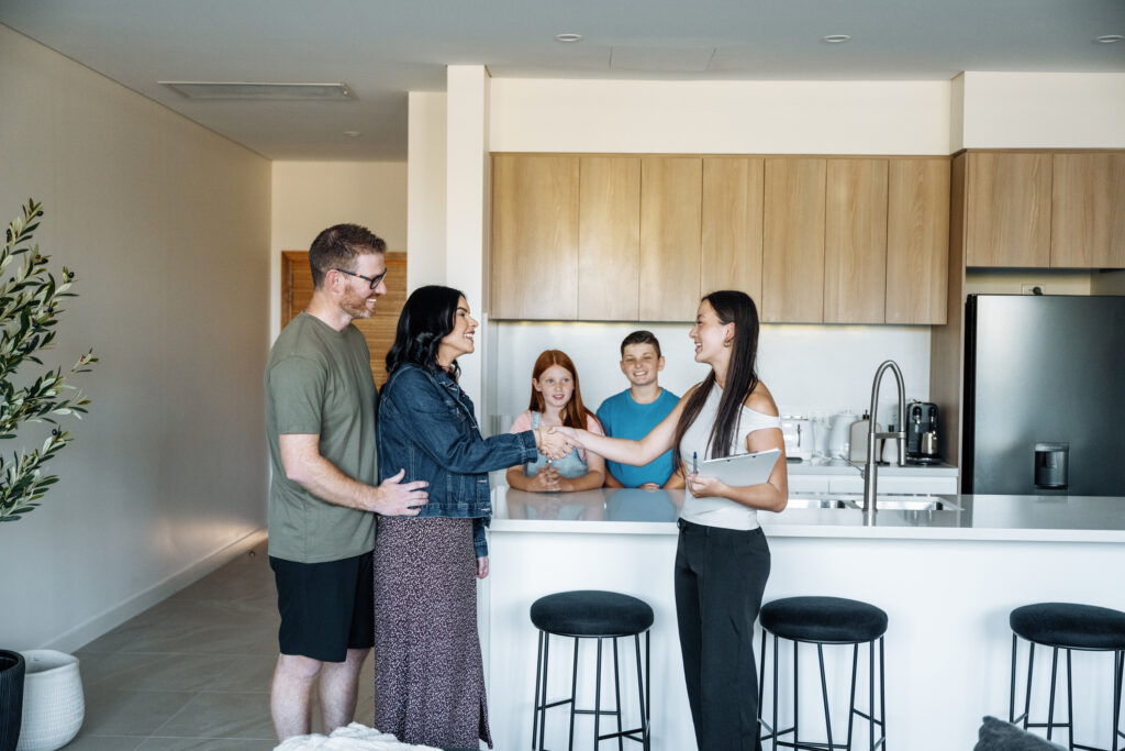 Familie im modernen Küchenbereich bei Begrüßung mit Handschlag zwischen zwei Frauen am Küchentresen
