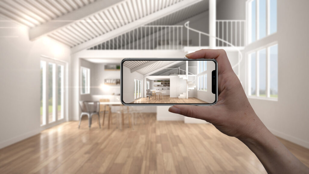Hand hält Smartphone, das eine digitale Visualisierung eines modernen Wohnraums mit Holzboden und Dachschrägen zeigt.
