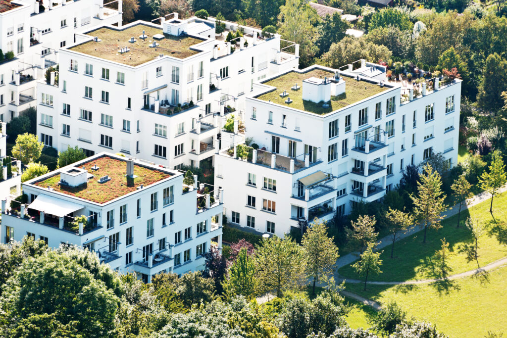 Moderne weiße Mehrfamilienhäuser mit begrünten Flachdächern in einer Wohnanlage