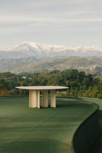 Minimalistischer Outdoor-Tisch vor Panorama aus Berglandschaft und Waldgebiet