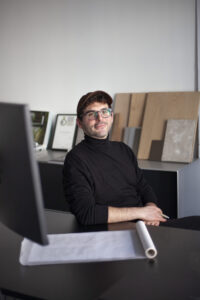 Architekt und Designer Emanuele ferraro im Büro mit Holz- und Oberflächenmustern im Hintergrund 