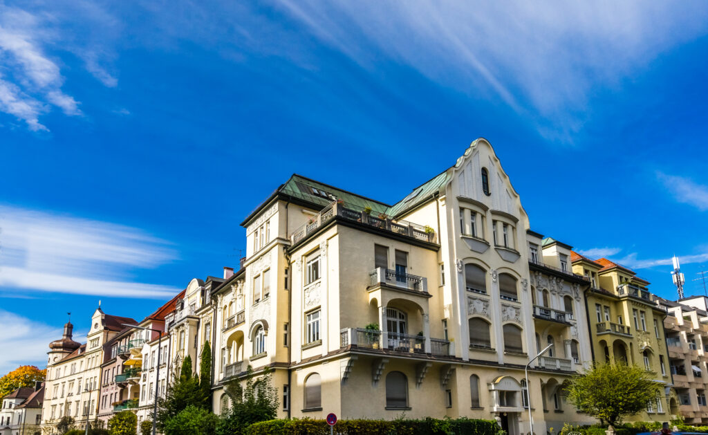 Helle Wohnhäuserzeile mit klassischer Architektur und begrüntem Straßenabschnitt bei Sonnenschein